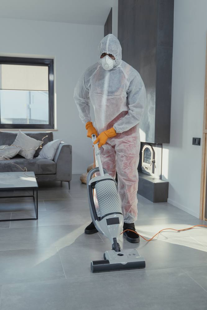 Deep-cleaning a living room with an upright vacuum near the sofa