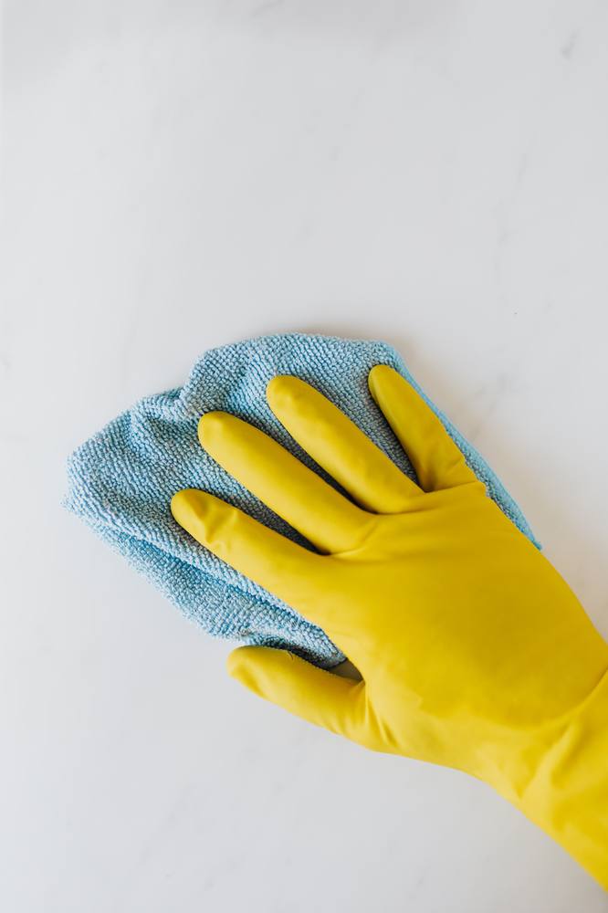 Close-up of a gloved hand wiping a surface with a microfiber cloth